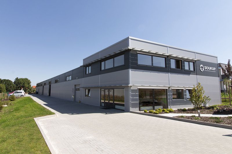 Exterior of the Soukup woodworking machinery building, a modern two-storey industrial unit with grey cladding and a paved for