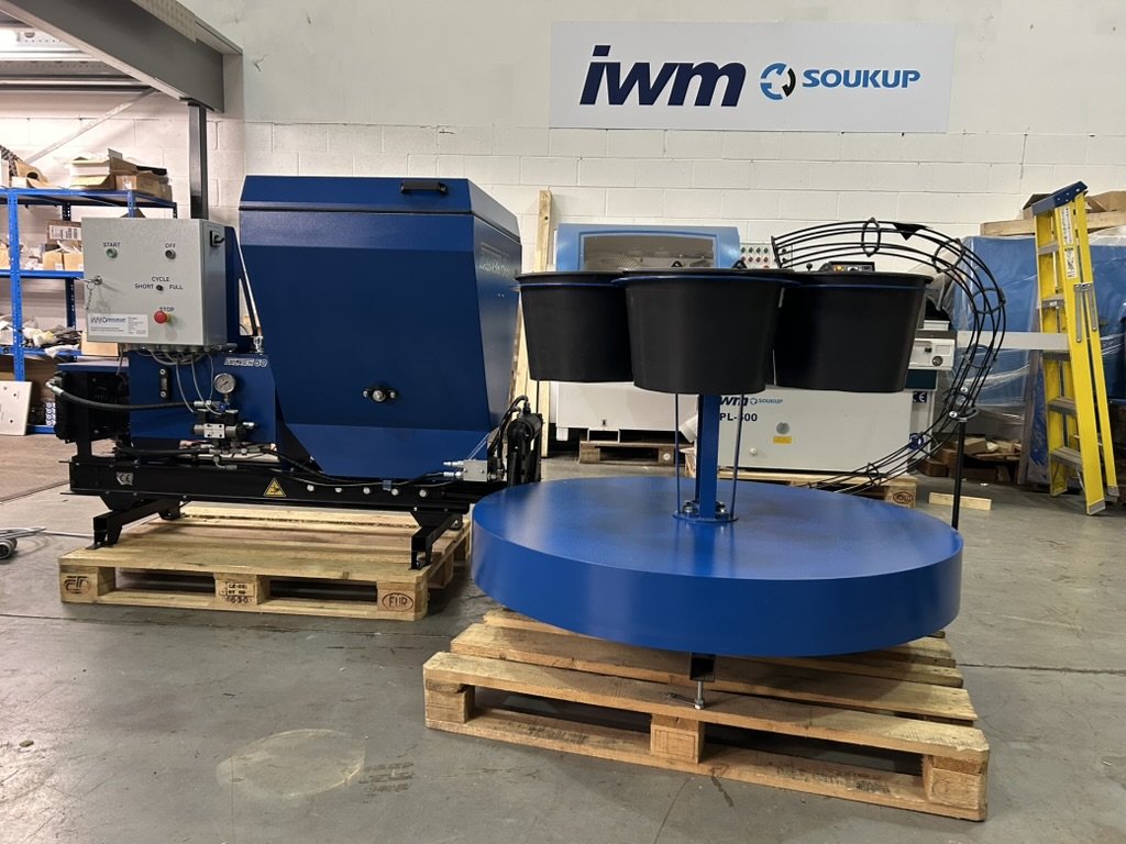 Two blue IWM Soukup industrial machines on wooden pallets inside a warehouse facility.