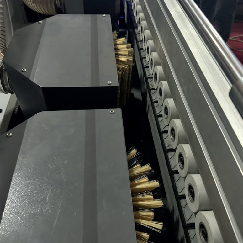 Close-up of industrial brushes and rollers along a conveyor track on a 3U SISAN machine