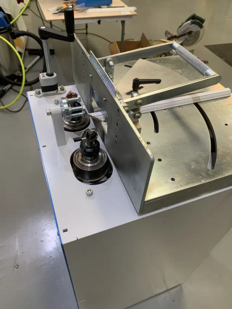Close-up of a Copenstick end scribe machine with metal bearings, clamps, and aluminium framing in a workshop