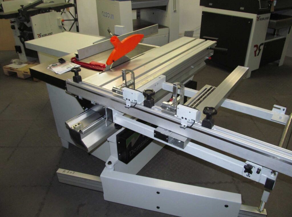 Dominion CP-16M panel saw with sliding table, rip fence, and orange blade guard in a workshop showroom
