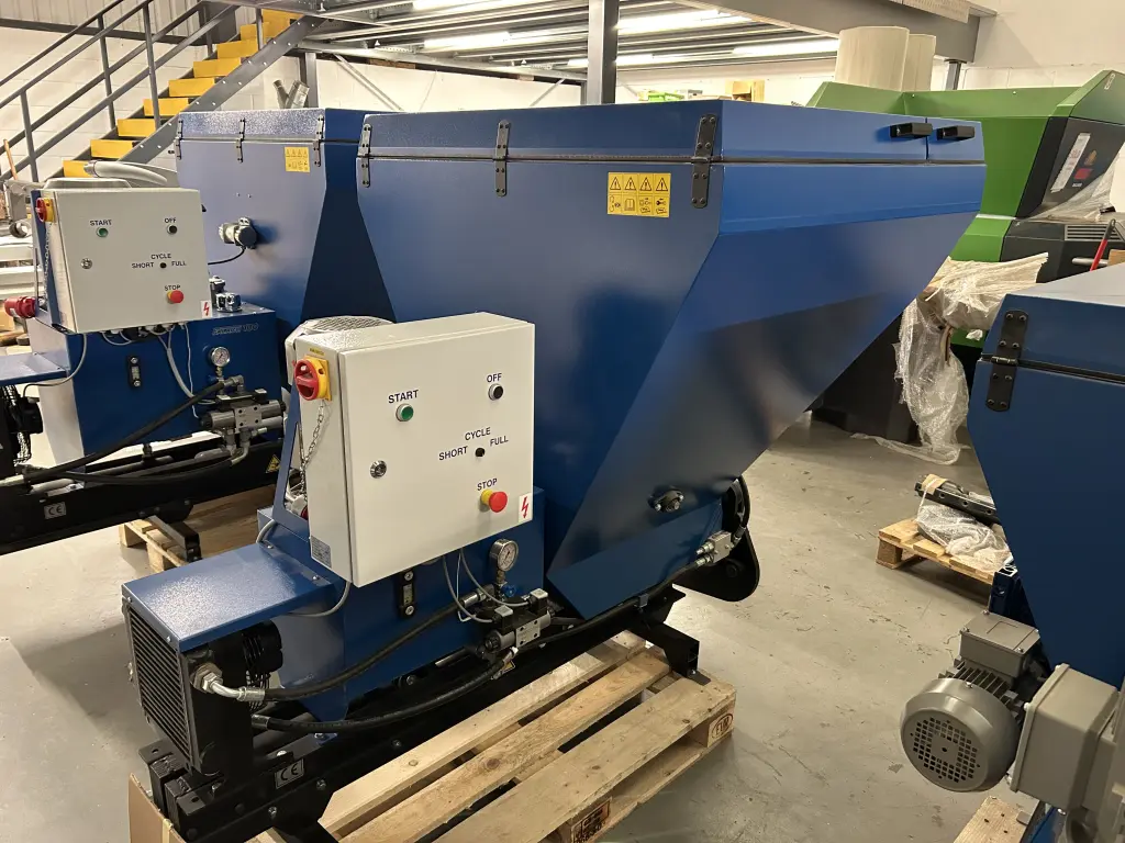 Falach 50XL briquette machine in blue on a wooden pallet, with a start/stop control panel and hydraulic components