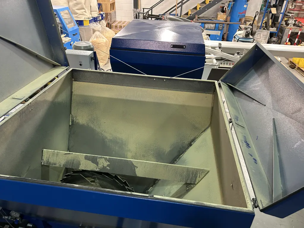 Open hopper of a Falach 50XL briquette machine containing shredded metal swarf, situated in an industrial workshop