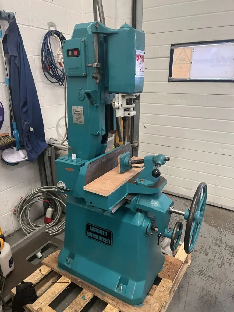 Wadkin Bursgreen chain morticing machine in teal, sitting on a wooden pallet in a workshop