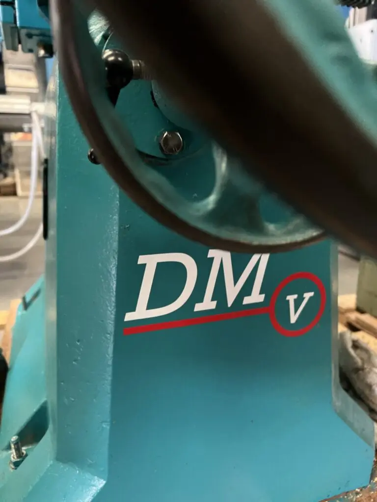 Close-up of a teal Wadkin DM/V vibrating chisel mortiser body, showing the branded DMV logo with red detailing.