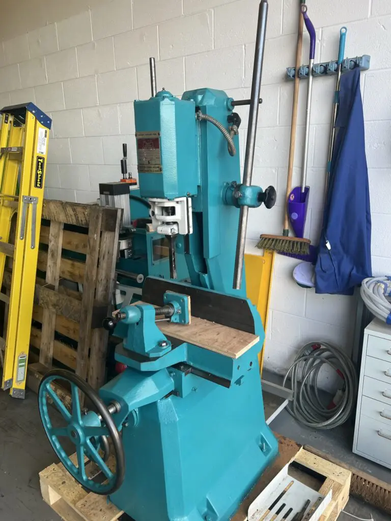Fully refurbished teal Wadkin DM/V vibrating chisel mortiser on a workshop floor beside a yellow ladder and cleaning tools