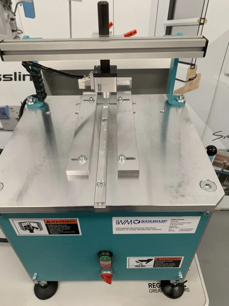 IWM Soukup HEP glazing bead end profile scribing machine with aluminium worktop, teal cabinet, and warning labels on castors
