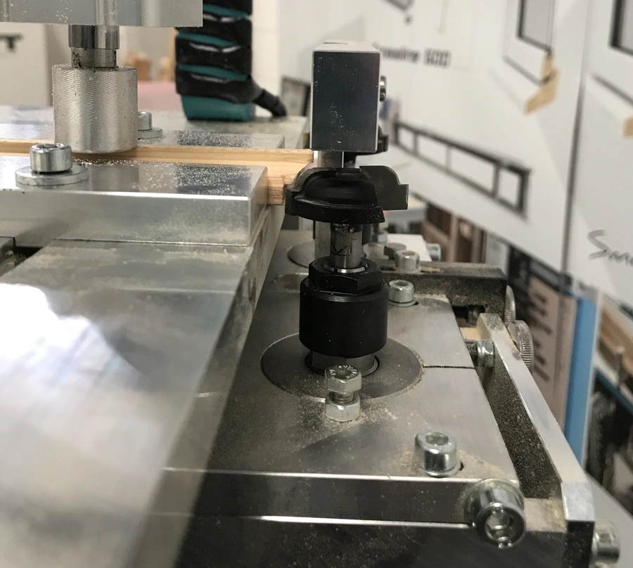 Close-up of a glazing bead end profile scribing machine cutting a timber wooden bead on a metal workbed