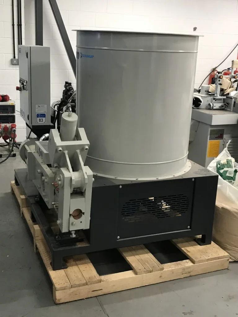IWM Soukup briquette machine mounted on a wooden pallet inside an industrial workshop