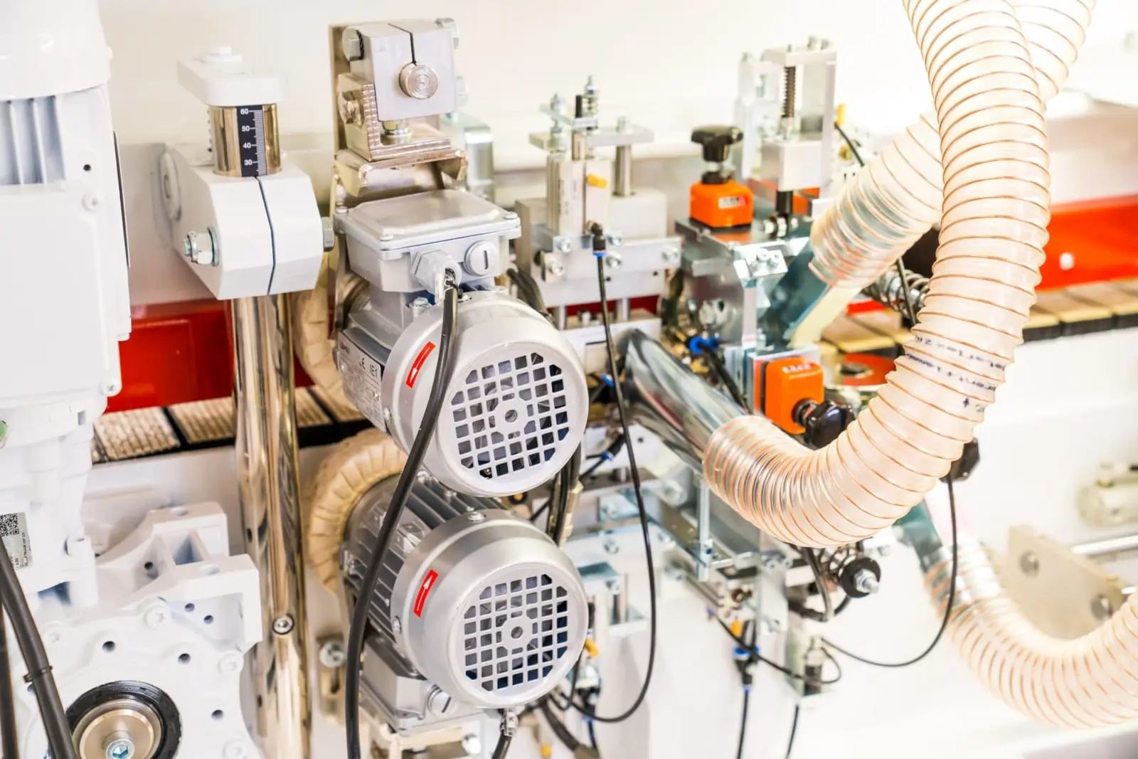 Close-up of dual electric motors, wiring, and a flexible dust extraction hose on a Lange B85KFE edge banding machine