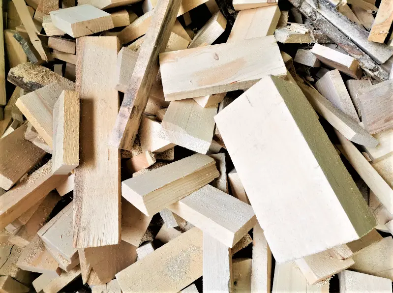 A large pile of pale, rough-cut timber offcuts and wood scraps scattered loosely together