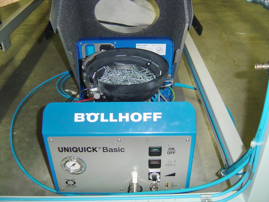 Böllhoff UNIQUICK Basic fastener feeding unit with a bowl filled with metal rivets and blue pneumatic tubing