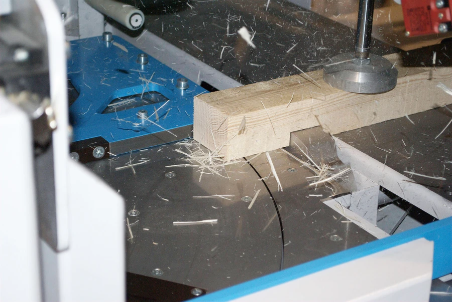 Timber being cross cut on a Soukup Crossline 650 saw bed, with wood shavings scattered across the metal surface