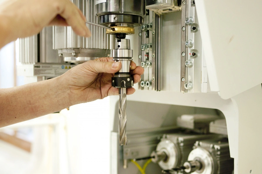 Technician fitting a spiral drill bit into the spindle chuck of a CNC machining centre