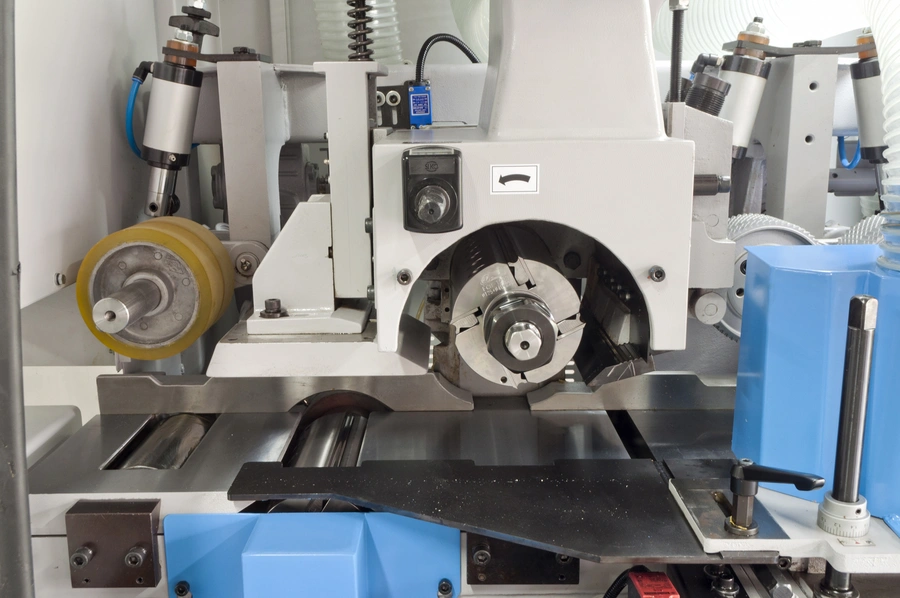 Close-up of a Soukup fourside planer and moulder spindle head with rotating cutter block and feed roller assembly