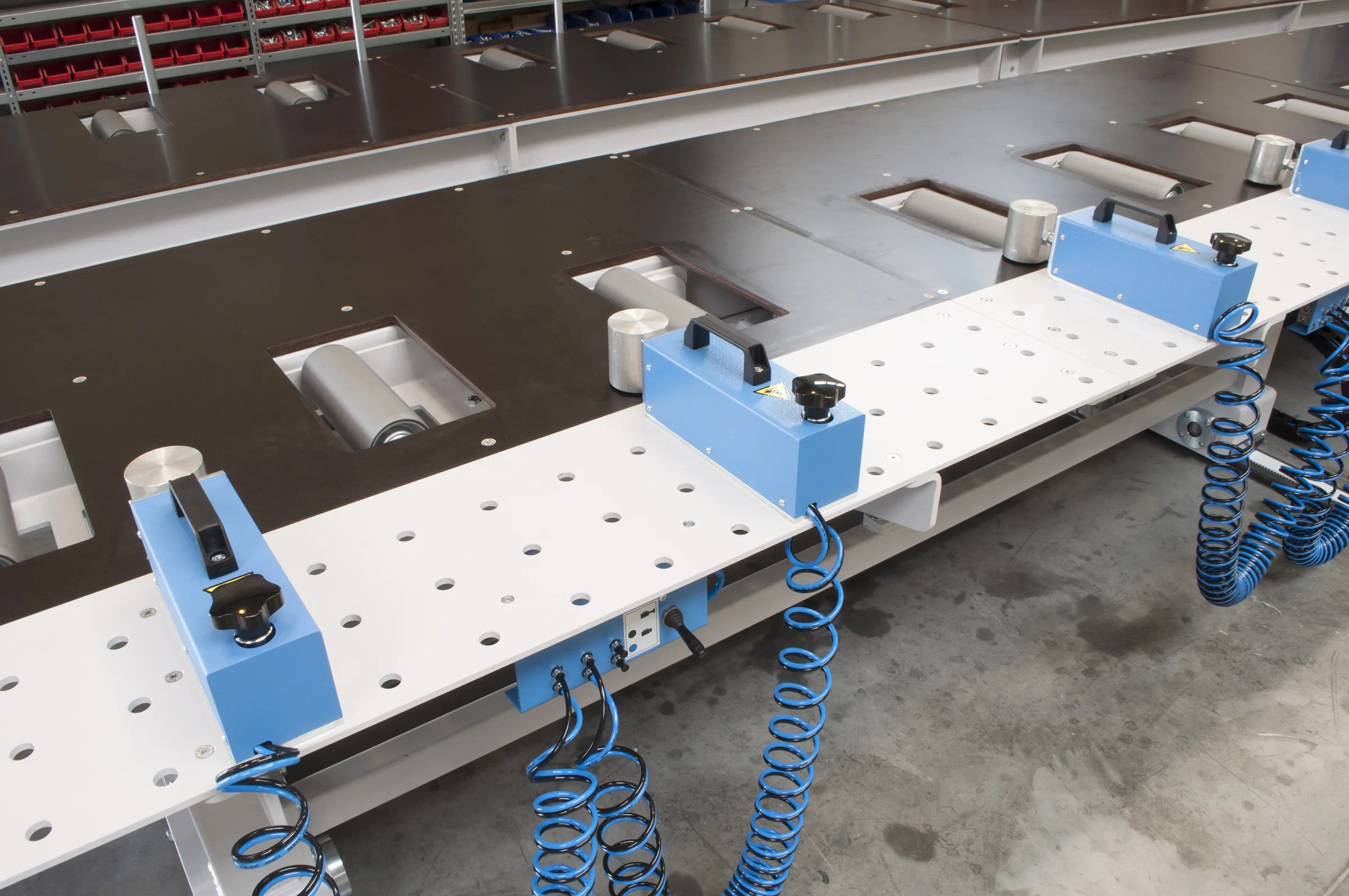 Industrial Soukup Framer Line with blue pneumatic hoses, roller inserts, and white perforated work surfaces in a factory setting
