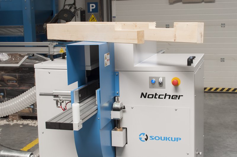 Soukup Notcher machine with a notched timber beam resting on top, in an industrial workshop setting.