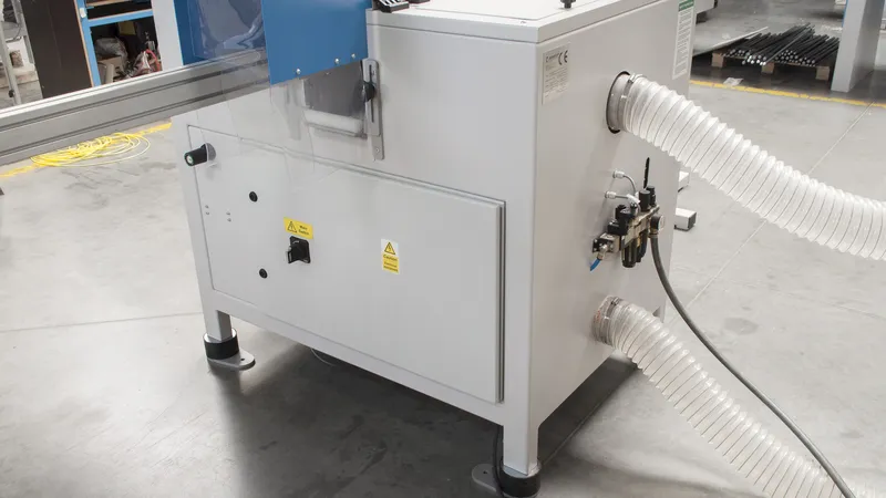 White industrial Soukup Notcher unit with flexible extraction hoses and warning labels, situated on a factory floor.