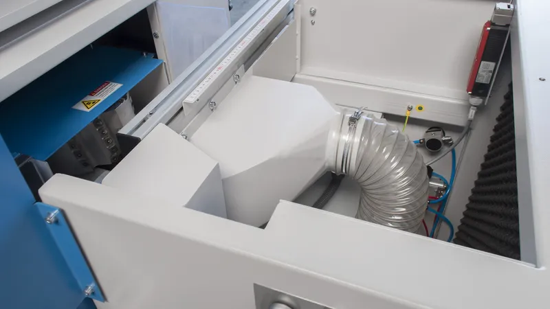 Interior of a Soukup Notcher machine showing a flexible ventilation duct, wiring, and white internal panels
