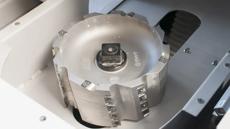 Close-up of a large cylindrical milling cutter head with carbide inserts mounted in a CNC notching machine
