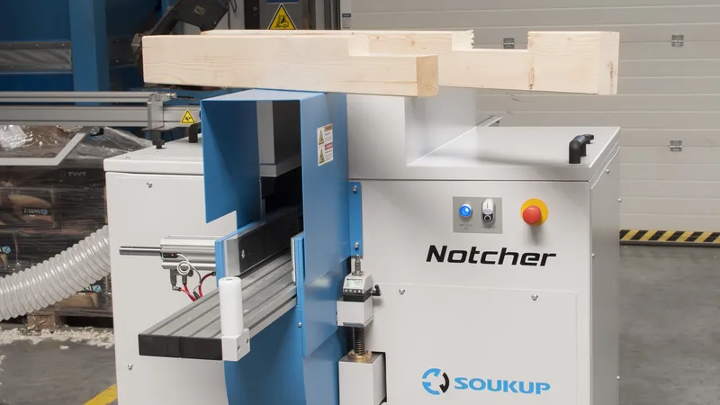 Soukup Notcher machine with a timber beam positioned above the blue and white woodworking unit in a workshop