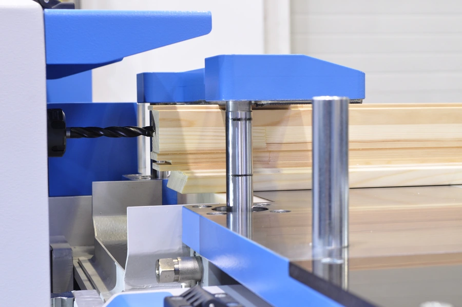 Blue Soukup Versa CNC window machine drilling into a timber window frame with a spiral drill bit