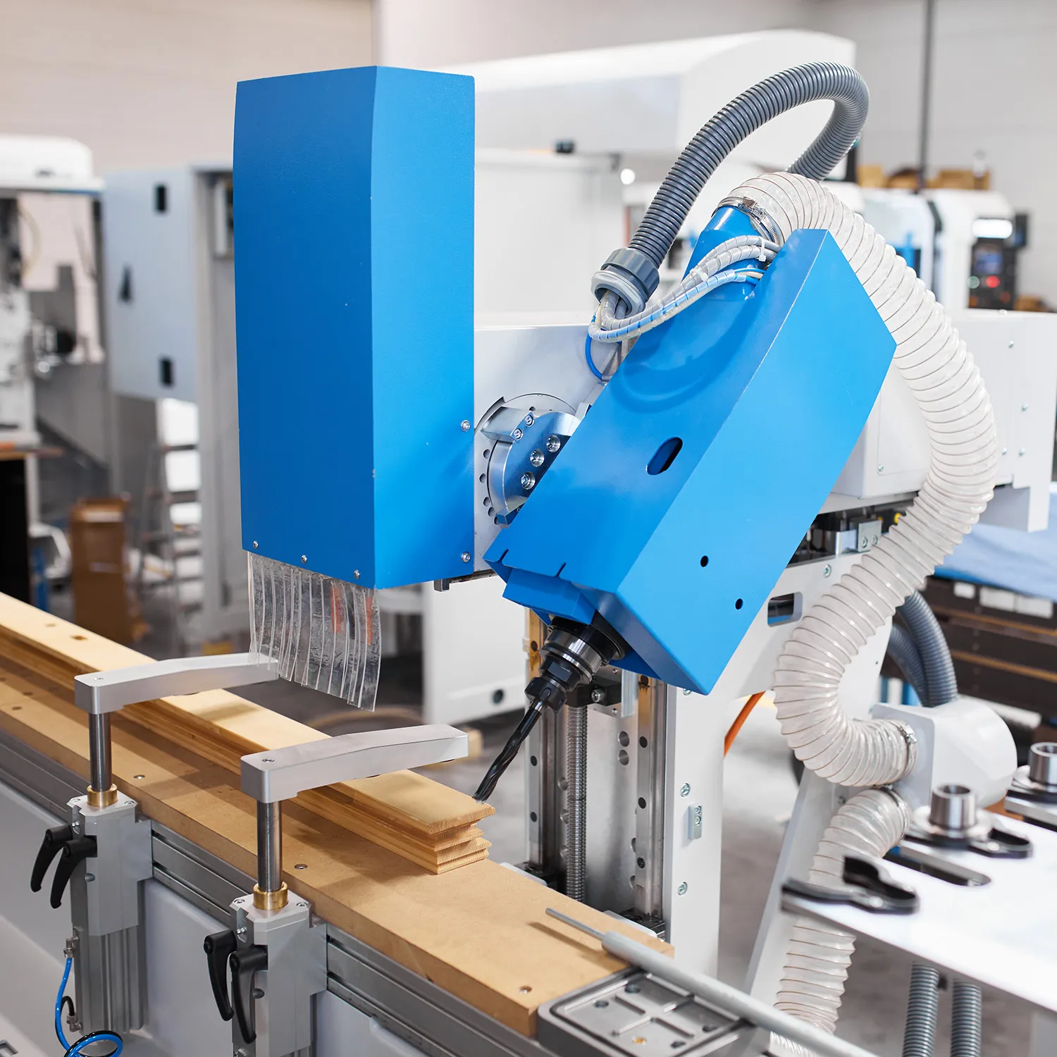 Blue tilting milling unit of the Soukup Versa Max angled over a clamped timber window section, with extraction hose and brush guard fitted