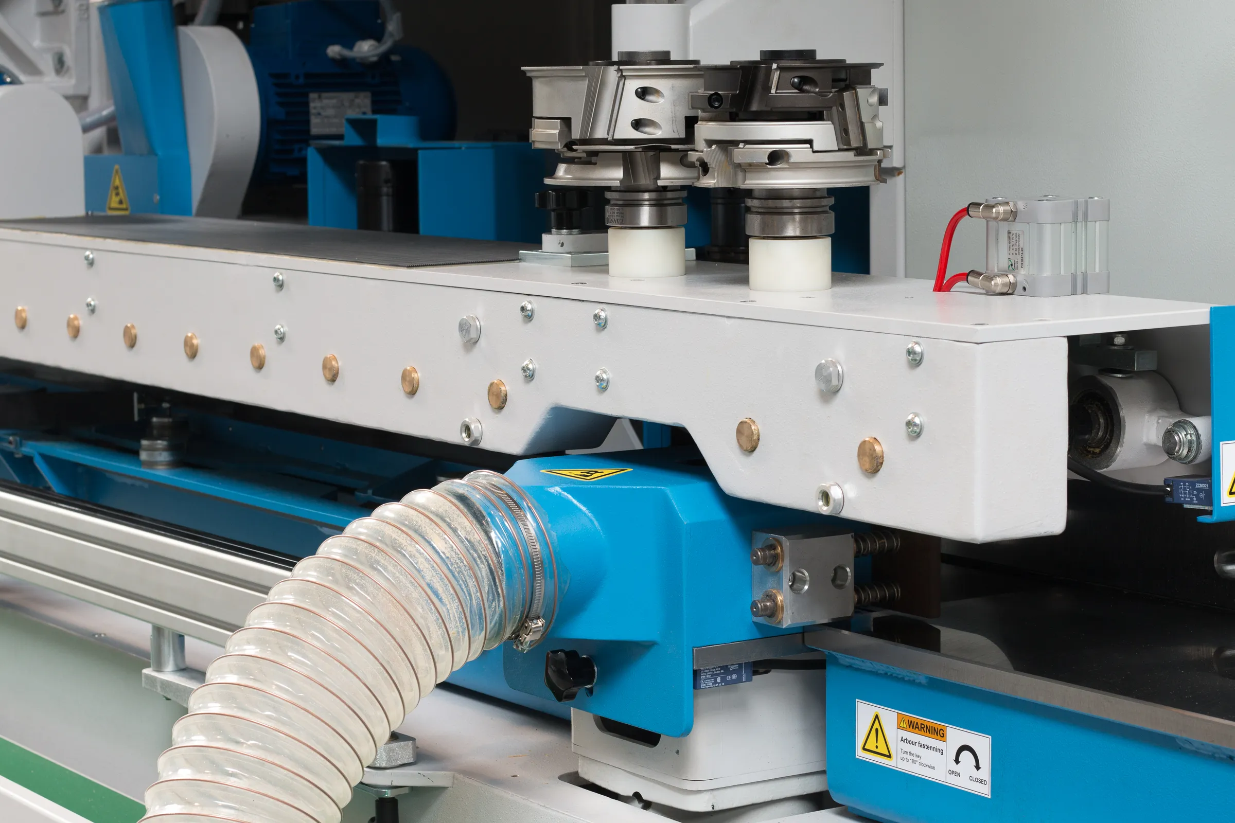 Close-up of the Soukup Wizard 3S CNC window machine showing spindle heads, dust extraction hose, and blue steel frame components