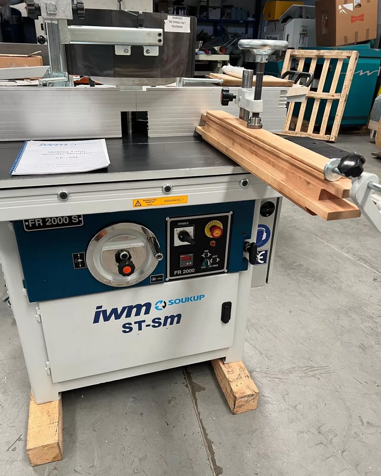 IWM Soukup ST-SM FR 2000 S sliding table spindle moulder with timber planks resting on the table in a workshop