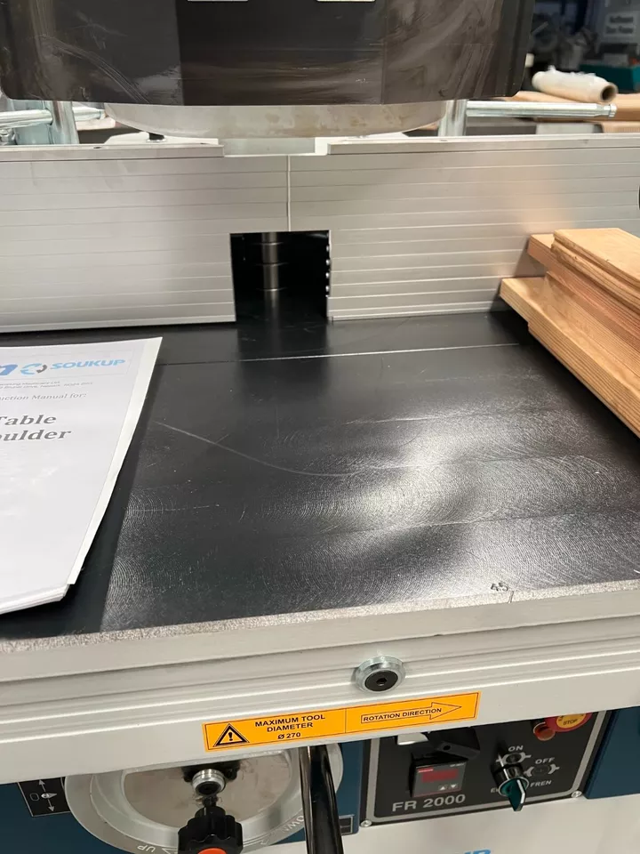 Soukup FR 2000 spindle moulder table with instruction manual and stacked timber boards in a workshop