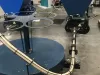 Two blue Falach 50 briquette machines with conveyor and circular turntable attachment on a workshop floor
