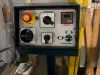 Industrial machine control panel with emergency stop button, spindle motor switch, main power dial, and height digital display in a workshop