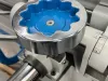 Close-up of a blue and silver handwheel adjustment knob on a heavy-duty surface planer machine with a rack and pinion mechanism visible below.