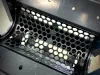 Close-up view of a perforated metal grate inside the open chamber of a robust industrial shredder machine
