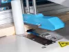 Close-up of a blue cutting head and blade assembly on a Soukup Crossline 500 cross cut saw processing a timber board