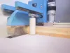 Soukup Crossline 500 cross cut saw cutting through a pine timber plank with dust visible beneath the blue blade guard