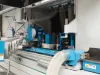 Interior view of a Soukup Wizard 3S CNC window machine showing blue motorised spindles, dust extraction hoses and warning labels