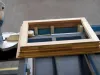 A pine wood frame assembled on a Soukup Assembling Table KS 2400, with clamping pins and a mitre saw visible nearby.