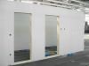 White timber frame wall panels with two open door openings under construction inside an off-site manufacturing facility