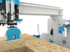 CNC machining centre with blue and white robotic arm processing an OSB wood panel