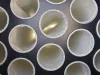Overhead view of multiple white cylindrical filter bags mounted on a dark metal panel inside a dust extractor unit