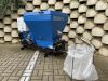 Falach 50 briquette machine in blue with control panel, hoses, and a white collection bag on a brick paved surface
