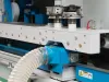 Close-up of the Soukup Wizard 3S CNC window machine showing spindle heads, dust extraction hose, and blue steel frame components