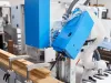 Blue tilting milling unit of the Soukup Versa Max angled over a clamped timber window section, with extraction hose and brush guard fitted