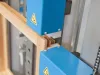 Close-up of a blue industrial window and door press machine clamping a wooden timber frame joint
