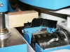 Close-up of a timber profile being shaped by a rotating cutter head and brush seals on a blue CNC window machine