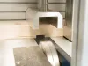 Close-up of a Soukup Crossline 500 cross cut saw blade cutting through a timber plank within a metal-framed machine.