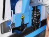 Close-up of a blue CNC window machining centre spindle unit with stacked cutter heads and a yellow hazard warning label