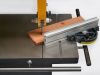 Closeup of an IWM UK bandsaw range machine cutting a copper-coloured workpiece on a metal table